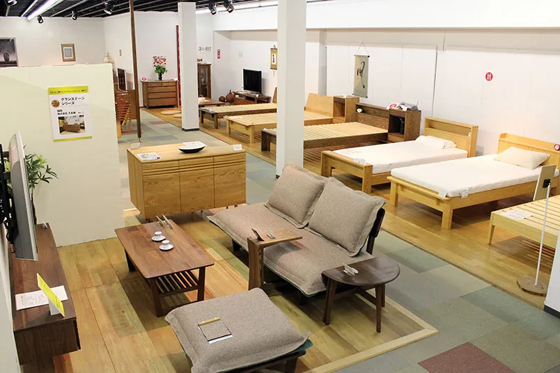 木製ベッドフレームとソファセットが展示されたショールーム