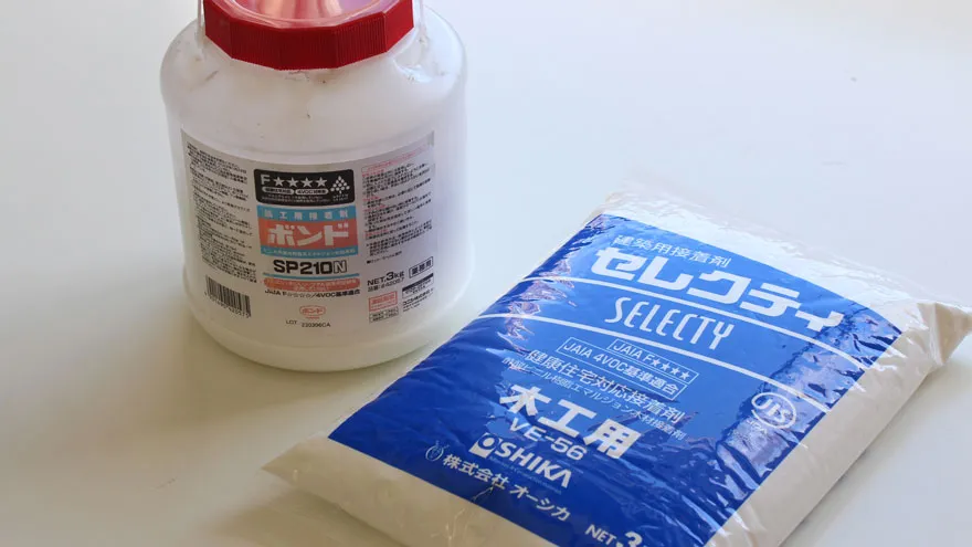 ボンドSP210ホワイトの白い容器と、セレクティ木工用接着剤の青いパッケージが並んで置かれている写真