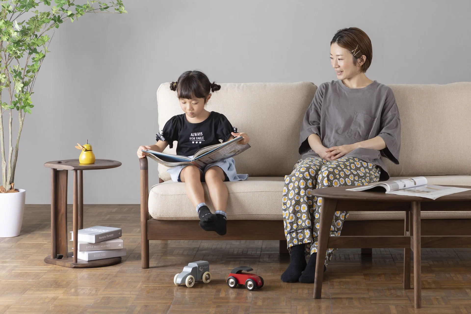 無垢材ソファで読書する親子、ナチュラルで安全なリビング空間