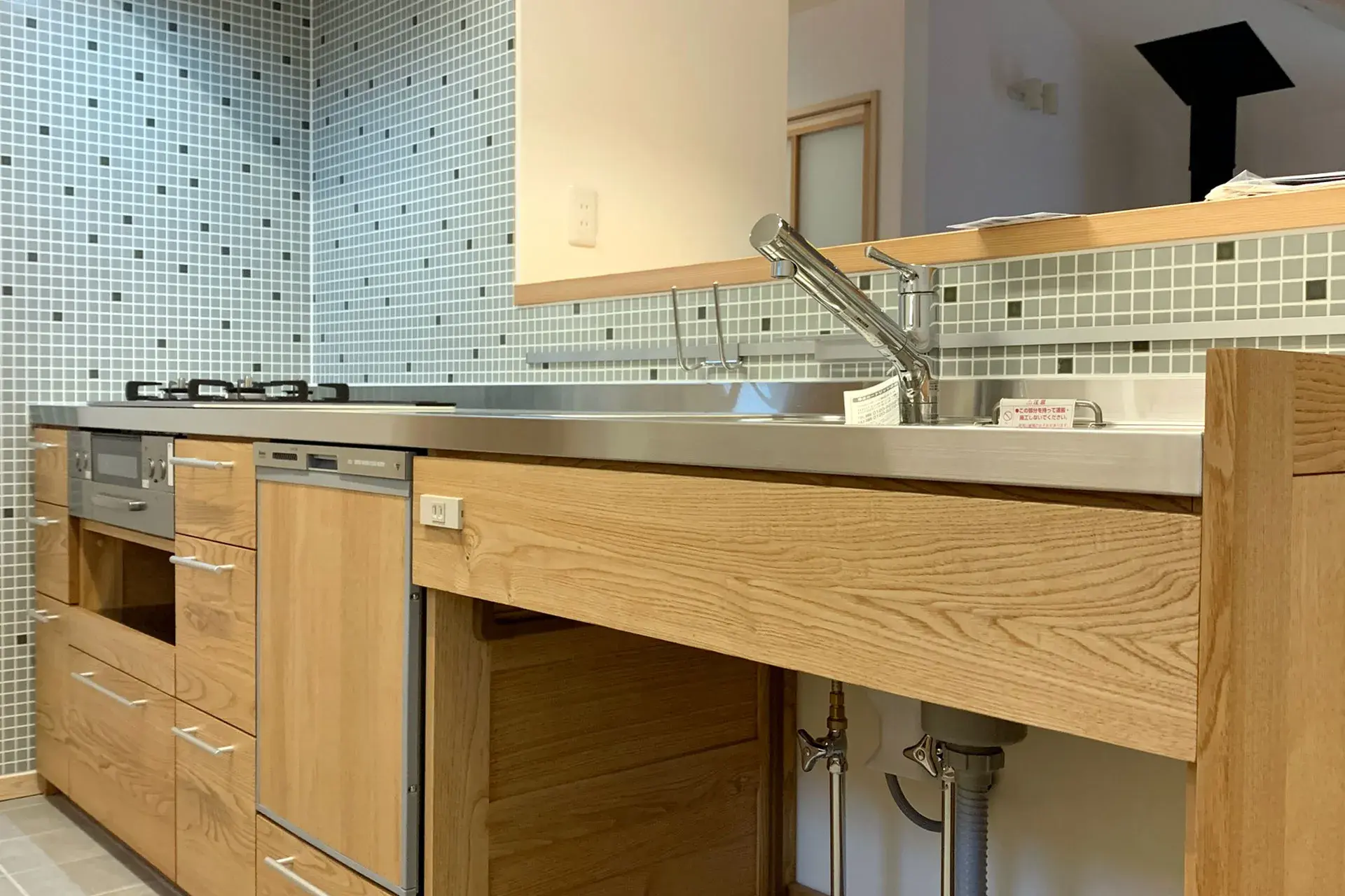 無垢材の木製キッチンとステンレス天板。モザイクタイル壁のナチュラルな台所。