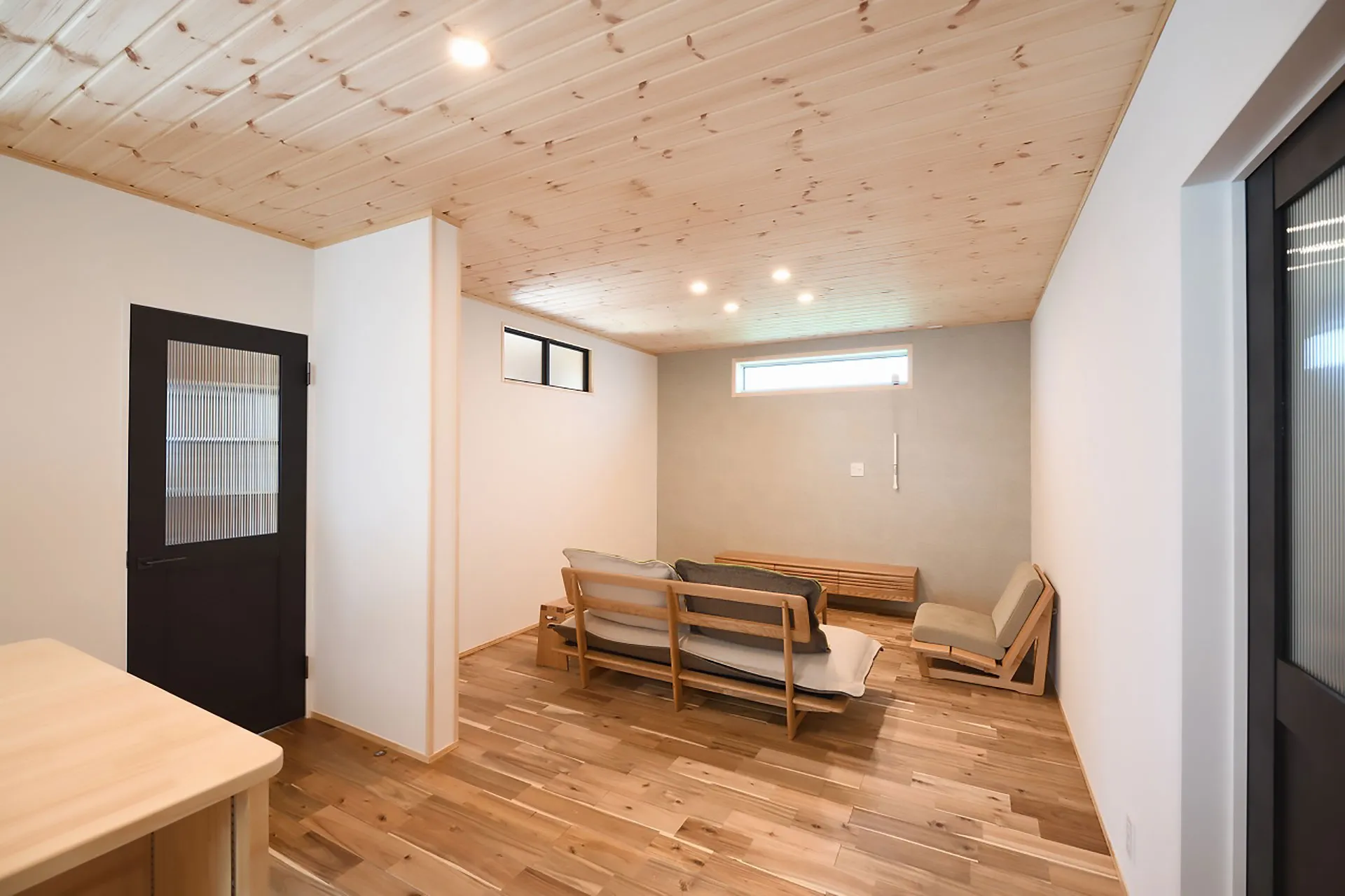 無垢材フローリングと木製ソファを配置したナチュラルモダンなリビングルーム。