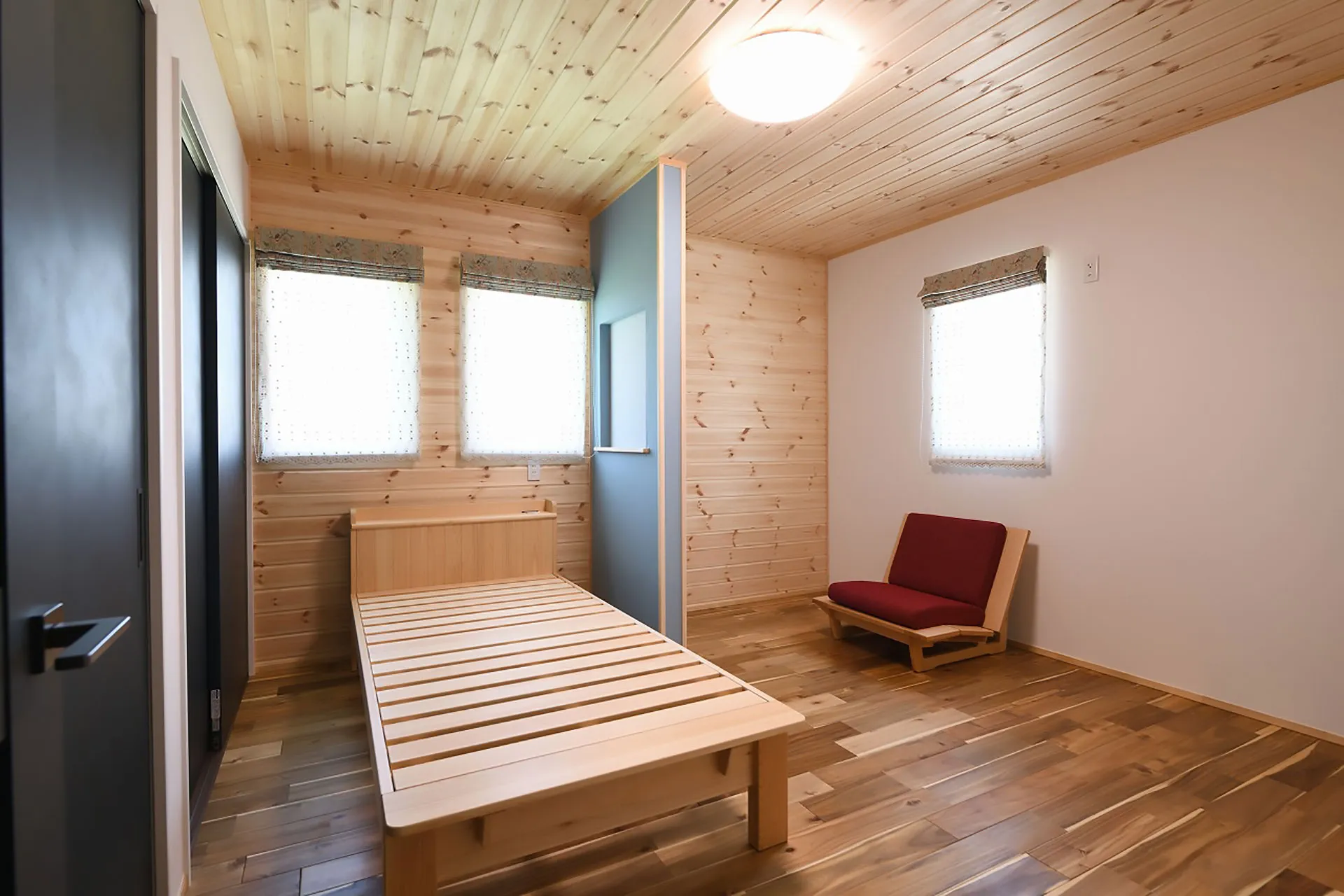 木製パネルの壁と無垢材ベッドがある寝室。自然素材の心地よい木の空間。