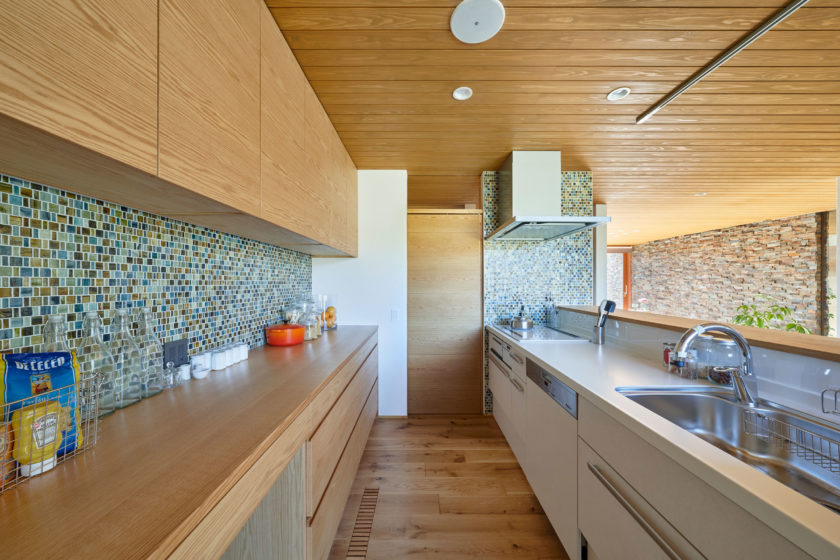 カラフルなモザイクタイルと無節のバックキャビネットが美しい。明るく開放的な対面式キッチン。