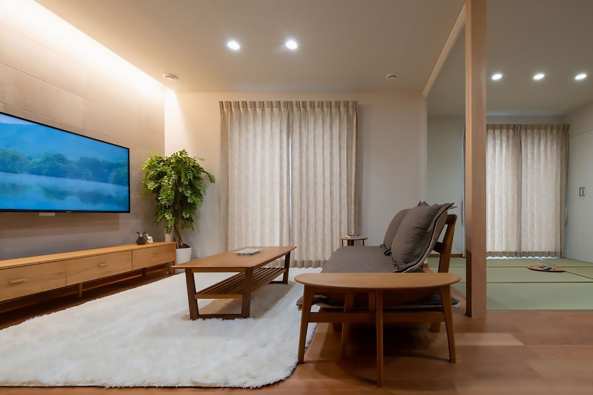 木製家具と白いラグが配置された、間接照明が優しい和モダンなリビング空間