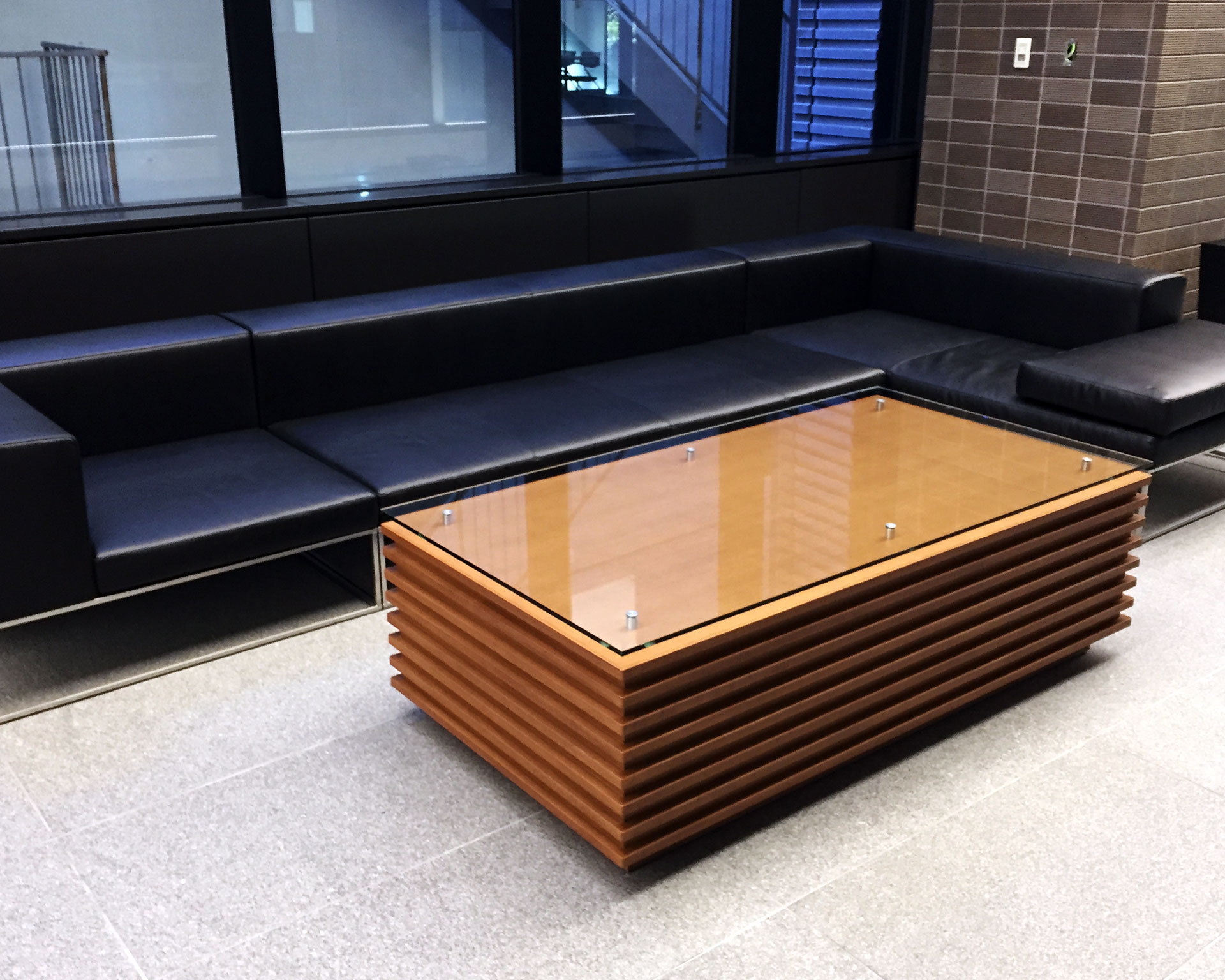 黒革ソファとガラス天板センターテーブルのある、落ち着いた雰囲気のラウンジ空間