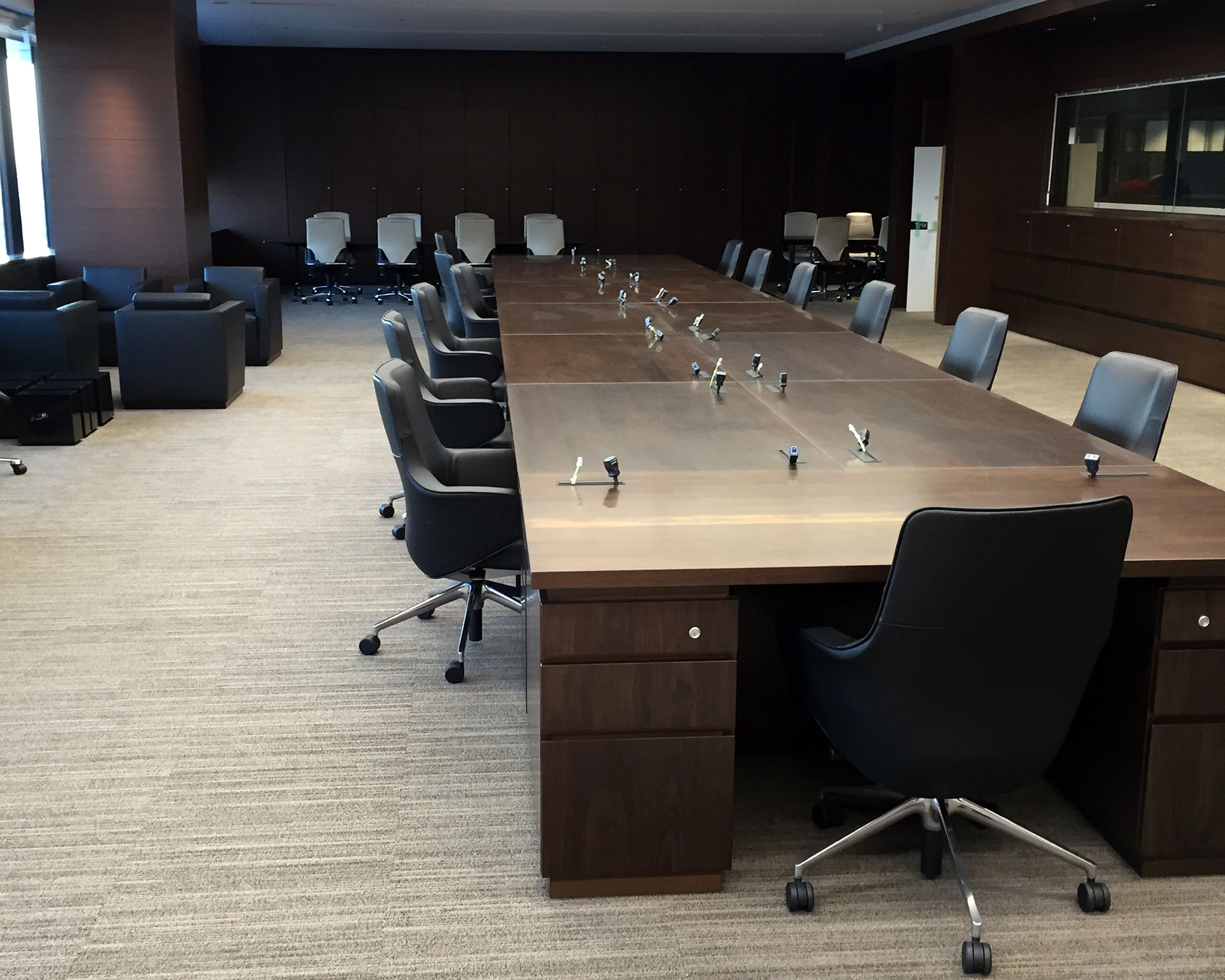 大型木製会議テーブルと黒革チェアが並ぶ、格調高いエグゼクティブ会議室