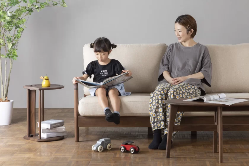 無垢材ソファで読書する親子。ナチュラルで安全なリビング空間